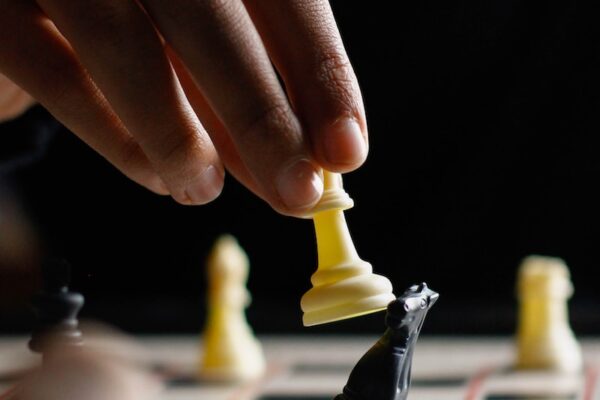 person holding white chess piece