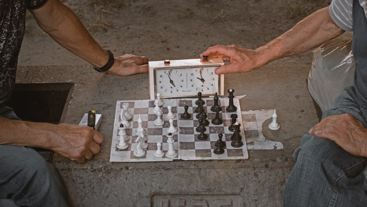 person playing chess on gray concrete floor