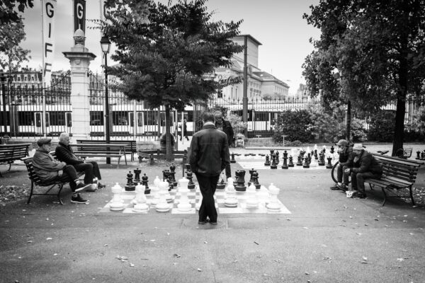 a man standing in front of a giant chess set