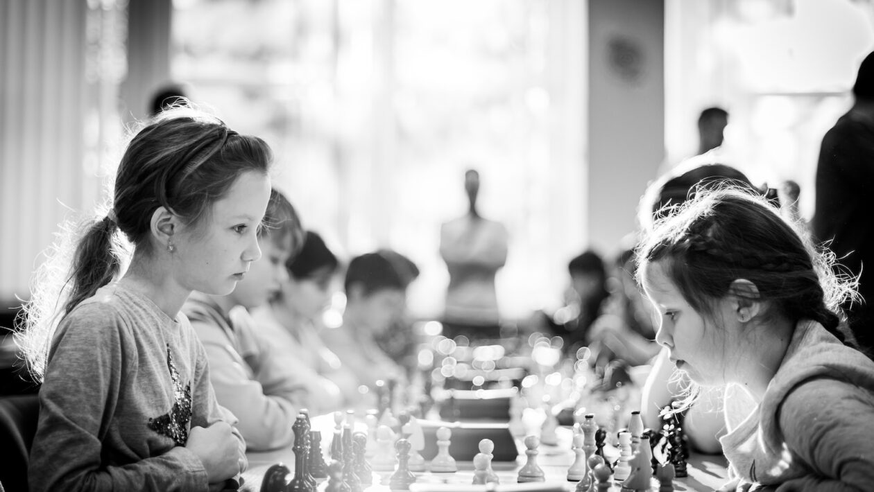 grayscale photography of children sitting while playing chess