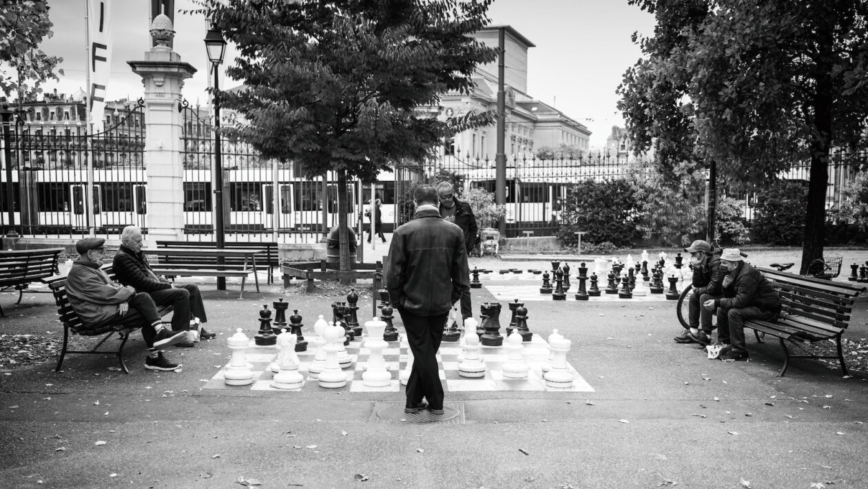 a man standing in front of a giant chess set